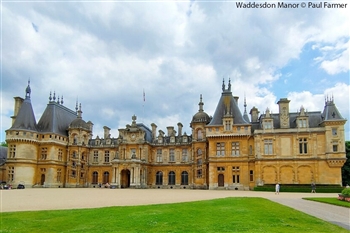 Image of a magnificent honey coloured manor house with grey turrets and a manicured lawn